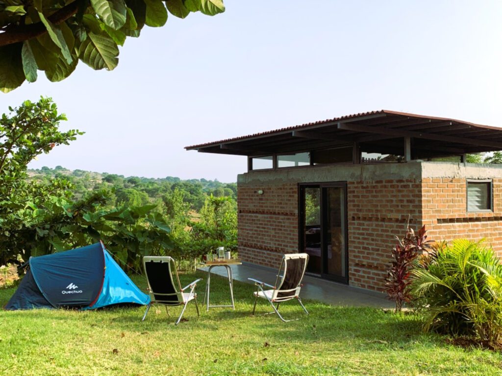 Eco friendly cottage of ecoland farms with two chair and camp surrounding by beautiful greenery and vast blue sky